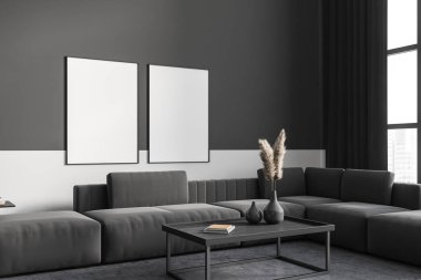 Dark grey living room interior with couch on concrete floor. Coffee table with decoration and dry plant, relax area in apartment. Two mock up canvases on wall. 3D rendering