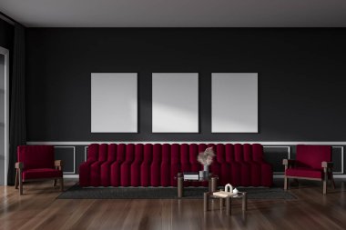 Dark living room interior with sofa and two armchairs with coffee table, carpet on hardwood floor. Chill space and three mockup posters in row on grey wall. 3D rendering