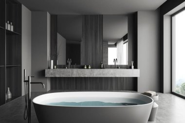 Dark bathroom interior with bathtub and water, double sink with accessories and grey concrete floor. Panoramic window on countryside. 3D rendering