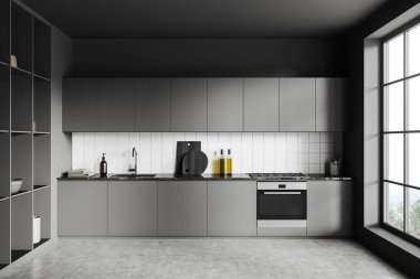 Front view on dark kitchen room interior with panoramic window, cupboard, grey wall, concrete floor, gas cooker, sink, cooking inventory, desks. Concept of minimalist design. 3d rendering