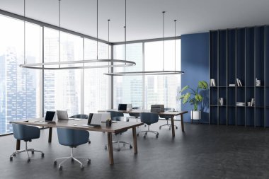 Dark coworking interior with armchairs and laptop on table, side view grey concrete floor. Workspace with panoramic window on Singapore skyscrapers. 3D rendering