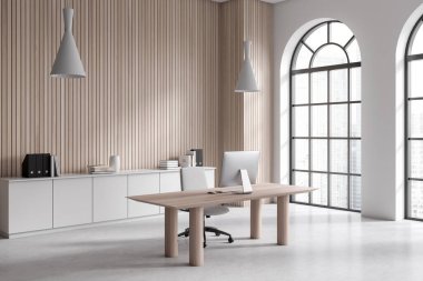 Modern office interior with pc computer on work desk, side view light concrete floor. Manager work corner with empty wooden wall, panoramic arched window on skyscrapers. 3D rendering