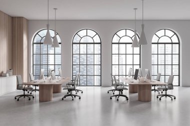Interior of stylish open space office with white and wooden walls, concrete floor, long wooden computer tables, white file cabinet and arched windows with blurry cityscape. 3d rendering