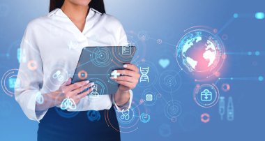 Unrecognizable young woman using tablet computer over light blue background with double exposure of blurry immersive medical interface. Concept of digital healthcare