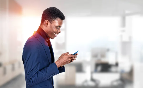 幸せな笑顔で若い黒人ビジネスマンのプロフィールは 背景にスマートフォン オフィスルームを参照してください ソーシャルネットワークとオンライン会議の概念 — ストック写真