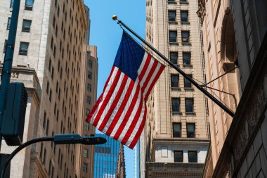 New York, Manhattan 'daki binaya karşı Amerikan bayrağı. Wall Street ve ABD bayrakları farklı binalar arasında