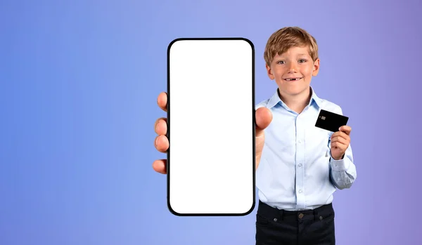 Uśmiechnięty Chłopczyk Kartą Kredytową Pokazujący Smartfona Makietą Niebieskim Tle Pojęcie — Zdjęcie stockowe