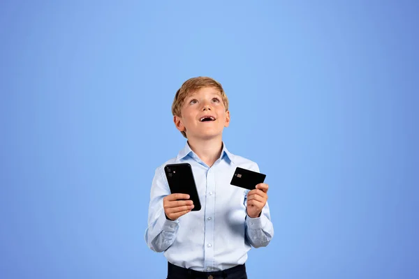 Elinde Telefon Kredi Kartı Olan Heyecanlı Bir Çocuk Yukarı Bakıyor — Stok fotoğraf