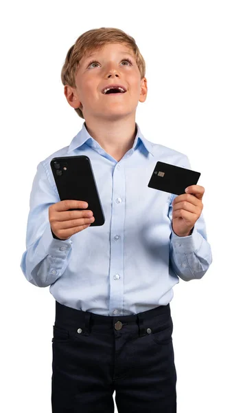 梦寐以求的孩子手里拿着电话和信用卡 抬起头来 白色背景上孤立的快乐肖像 网上购物和网上银行的概念 — 图库照片