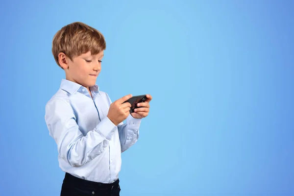 Portrét Vážného Chlapečka Který Používá Smartphone Modrém Pozadí Koncept Internetu — Stock fotografie