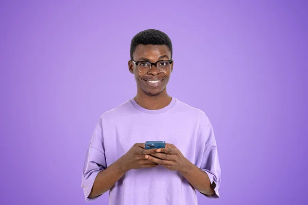 手に携帯電話を使用して幸せな黒人男性は 空のコピースペース紫色の背景にカメラを見て肖像画 オンラインショッピング ソーシャルメディア コミュニケーションの概念 — ストック写真