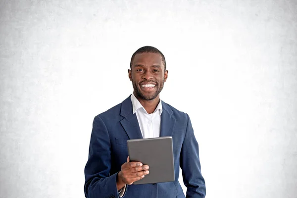 コンクリート壁の背景の上にタブレットコンピュータを保持若いアフリカ系アメリカ人のビジネスマンの笑顔 インターネット接続の概念 — ストック写真