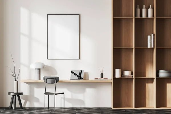 stock image Interior of modern home office with white walls, dark wooden floor, wooden table with laptop and vertical mock up poster above it and wooden bookcase. 3d rendering