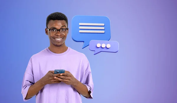 音声泡と紫色の壁の近くにスマートフォンを保持眼鏡で陽気な若いアフリカ系アメリカ人の男性の肖像画 コミュニケーションやソーシャルメディアの概念は — ストック写真