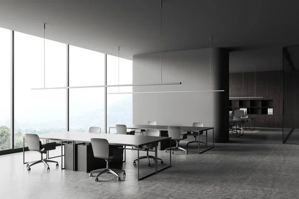 stock image Dark business interior with shared table and chairs, side view coworking zone behind partition. Workspace corner with panoramic window on countryside. 3D rendering