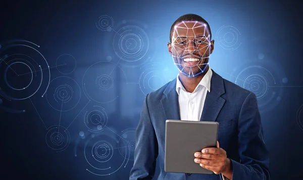 笑顔の髭を生やしたアフリカ系アメリカ人ビジネスマンは オフィスの背景に没入感のある顔認識インターフェースを備えたタブレットを使用しています 生体計測の概念 — ストック写真
