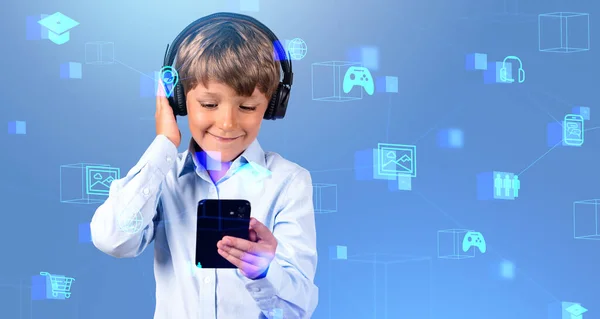 青い背景にぼやけたソーシャルメディアのアイコンの二重露出でスマートフォンやヘッドフォンを使用して小さな男の子を笑顔 教育と楽しみのための技術の概念 — ストック写真