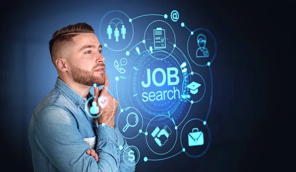 Portrait of pensive bearded man in casual clothes standing over dark blue background with blurry job search interface. Concept of recruitment