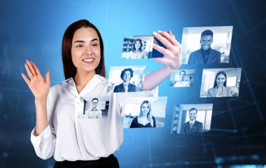 Ofisteki kadın akıllı telefon kullanıyor ve video görüşmesinde ortaklarına el sallıyor. Mavi Hud, farklı insanlarla parlayan hologram, çift pozlama. Sosyal medya ve ağ kavramı
