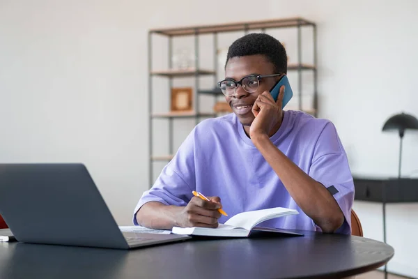 電話で黒人ビジネスマンの笑顔 ノートブックと机の上に契約とコンピュータ 背景がぼやけて棚付きのオフィスルーム コミュニケーションの概念 — ストック写真
