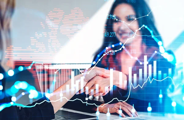 Businesswomen shake hands in office room. Double exposure of forex diagrams, stock market candlesticks and earth map. Concept of worldwide network