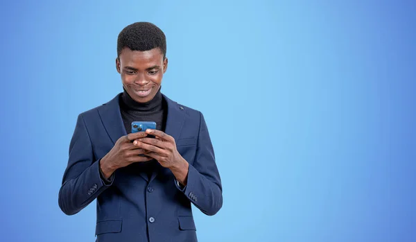 青い背景の上に立ってスマートフォンを使用して若いアフリカ系アメリカ人ビジネスマンの笑顔の肖像画 コミュニケーションの概念 モックアップ — ストック写真