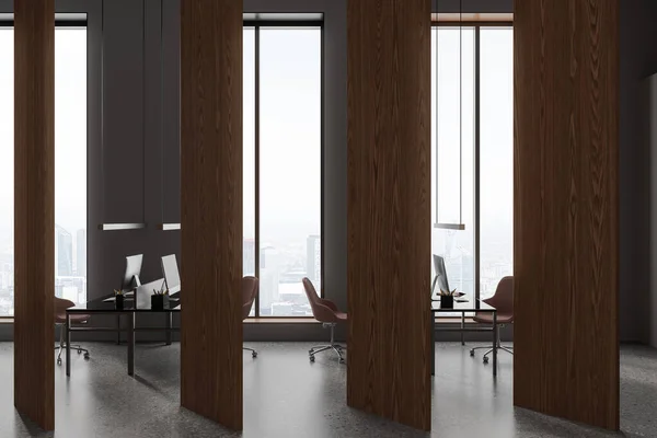 Dark office interior with pc computer on desk with armchairs in row, grey concrete floor. Coworking zone with long wooden partition, panoramic window on skyscrapers. 3D rendering