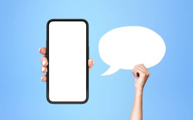 Akıllı telefonlu bir kadın, mavi arkaplanda boş bir konuşma balonu olan uzay ekranını taklit ediyor. Sosyal medya ve reklam kavramı