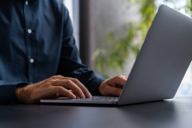 Tanımlanamayan iş adamının elleri bulanık ofiste karanlık masalı dizüstü bilgisayar kullanıyor. Teknoloji ve iş iletişimi kavramı