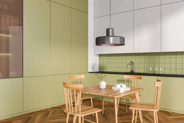 Green kitchen interior with wooden dinner table and seats, side view hardwood floor. Modern cooking and eating corner in home apartment. 3D rendering