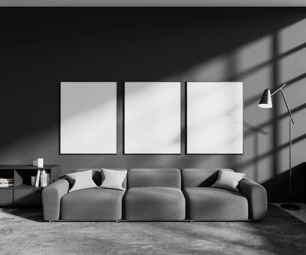 风格新颖的客厅内饰有灰色墙壁 混凝土地板 舒适的灰色沙发和悬挂在上面的三个垂直的模拟海报框架 3D渲染 — 图库照片