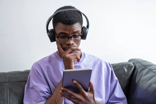 Fiatal Meglepett Afrikai Férfi Amint Táblagépet Néz Kéz Kézben Fejhallgatóban — Stock Fotó