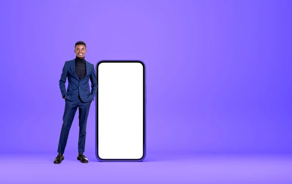 黒のビジネスマンの笑顔 フル長さ スマートフォンの大規模なモックアップコピースペース画面 紫色の背景の近くに立っている ネットワークとソーシャルメディアの概念 — ストック写真