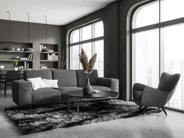 Dark living room interior with sofa and armchair with coffee table, side view, grey concrete floor. Shelf with decoration and dining area. Panoramic window on Singapore city view. 3D rendering