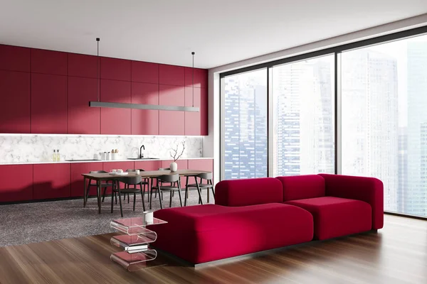 Red home studio interior with sofa and dinner table with chairs, side view. Cooking and lounge zone with panoramic window on Singapore skyscrapers. 3D rendering