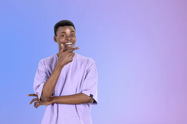 カジュアルな服装をしたアフリカ系アメリカ人ビジネスマンの笑顔が背景に空の紫色の壁の近くに彼のあごに触れて立っている モデルの概念 成功したビジネス人 ブレインストーミング 創造的なアイデア — ストック写真