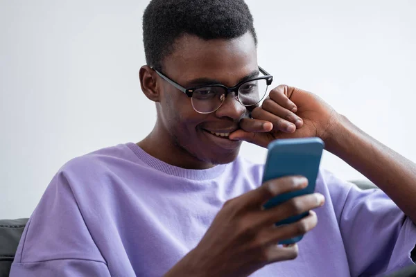 ブラック笑みを浮かべて男は 携帯電話を見て 手にデバイスを使用して オンラインでインターネットやソーシャルメディアを閲覧できます ネットワークとモバイルアプリの概念 — ストック写真