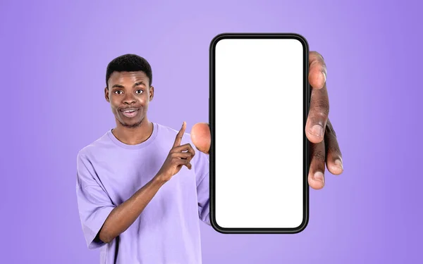 若い黒人男性の手を示すと指のスマートフォンを指して 紫色の背景に大きなモックアップコピースペース画面 新しいウェブサイトやソーシャルメディアの概念 — ストック写真