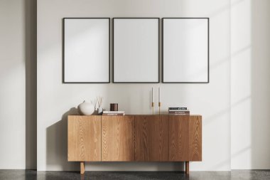 Minimalist oturma odasının içi ahşap büfe ve sanat dekorasyonuyla dolu. Sıcak İskandinav tasarımı ve gri beton zemin. Sıraya dizilmiş üç tane tuval posteri. 3B görüntüleme