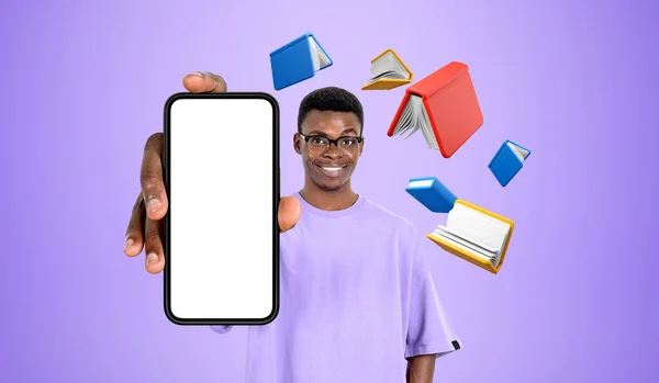 本で紫色の背景にモックアップ画面でスマートフォンを示す若いアフリカ系アメリカ人男性 デジタル図書館とEラーニングの概念 — ストック写真