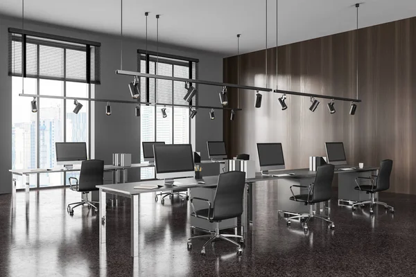 stock image Modern coworking interior with armchairs and pc computer on desk in row, side view grey concrete floor. Business office room and panoramic window on skyscrapers. 3D rendering