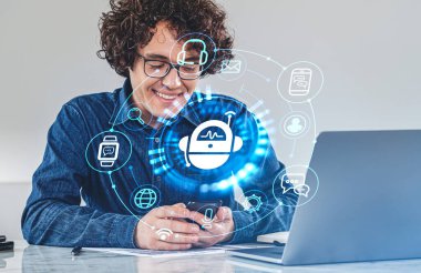İşadamı elinde çeşitli hologramlarla dijital arayüzlü akıllı telefon tutuyor. Robot, akıllı saat, kulaklık, mesaj. Dizüstü bilgisayarı ve masası olan bir ofis. Sosyal medya kavramı, çalışma süreci