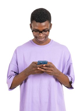 Telefonla yazı yazan mutlu bir Afrikalı adam, mor tişörtlü bir portre. Çevrimiçi internet, beyaz arka planda izole edilmiş. Çevrimiçi alışveriş ve sosyal medya kavramı