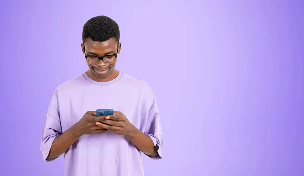 笑顔の黒人男性が電話で閲覧し 空のコピースペースの紫色の背景にデバイスを入力します オンラインショッピング 購入の概念 — ストック写真