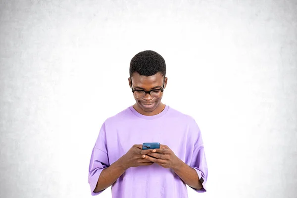 コピースペースの灰色のコンクリートの壁の背景に携帯電話で入力し 閲覧し インターネットで研究する幸せなアフリカ人男性 ソーシャルメディア モバイルアプリの概念 — ストック写真