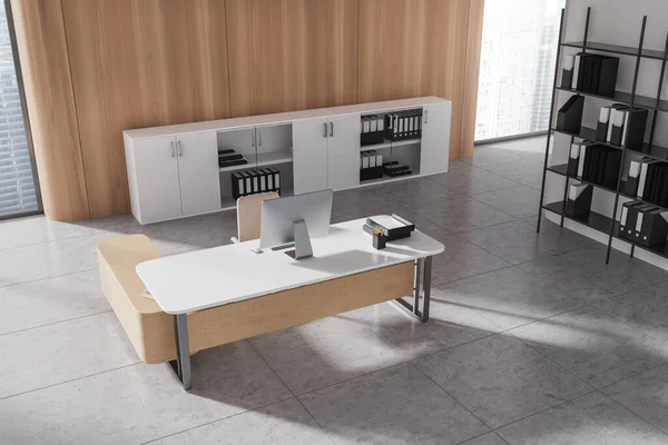 Top view of office room interior with desk and armchair on grey tile concrete floor. Pc computer and sideboard with business folders. Panoramic window on skyscrapers. 3D rendering