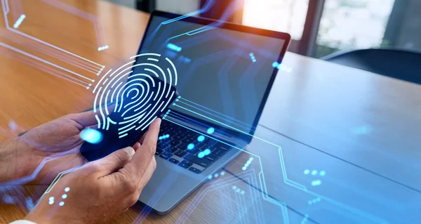 Hands of unrecognizable businessman using smartphone and laptop in office with double exposure of fingerprint interface. Concept of data protection and biometric authentication