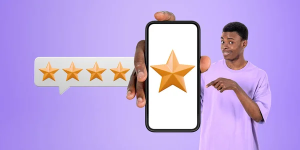 Cheerful young African American man in casual clothes showing smartphone with five start rating over purple background. Concept of product and service quality ranking
