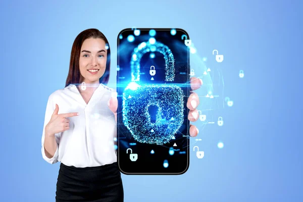 微笑的女商人手指指向有网络安全全息图的大型智能手机屏幕 蓝色背景的全球数据保护 安全和技术概念 — 图库照片