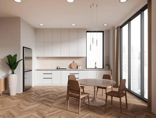 Beige home kitchen interior with dinner table, chairs and cooking area with kitchenware and fridge. Minimalist eating zone with panoramic window on skyscrapers. 3D rendering